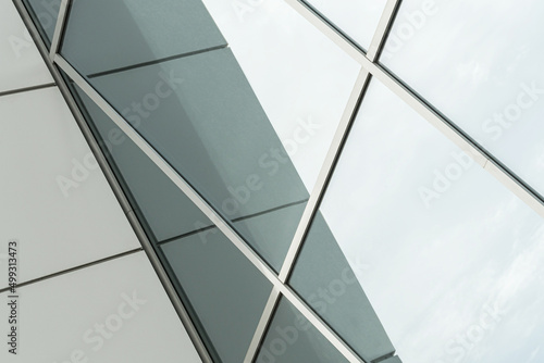 Geometric colored building facade elements with planes, lines and corners with light flare and reflections for an abstract background and texture of white, blue, gray colors. Place for text