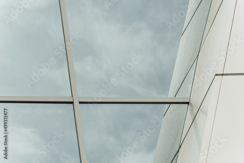 Geometric colored building facade elements with planes, lines and corners with light flare and reflections for an abstract background and texture of white, blue, gray colors. Place for text