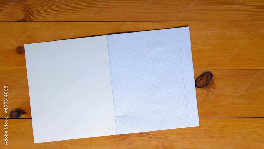 School teacher lays out a checkered notebook for mathematics, ruler, triangle, protractor, pen, pencil on a wooden table in the school classroom. Copy space for text. Blank sheet math page. Top view School teacher lays out a checkered notebook for mathematics, ruler, triangle, protractor, pen, pencil on a wooden table in the school classroom. Copy space for text. Blank sheet math page. Top view