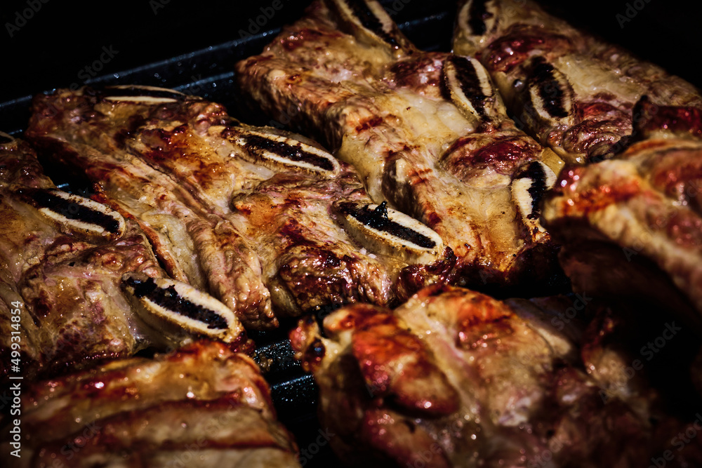 juicy beef rib and pork rib slowly being made on the grill on the fire at a gas barbecue juicy beef rib and pork rib slowly being made on the grill on the fire at a gas barbecue