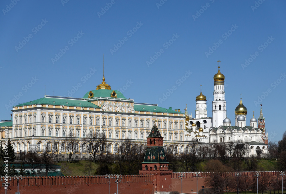 Grand Kremlin Palace of Moscow Kremlin and Ivan the Great Bell Tower behind the red brick wall on bright spring sunny day