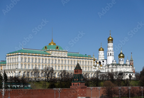 Grand Kremlin Palace of Moscow Kremlin and Ivan the Great Bell Tower behind the red brick wall on bright spring sunny day