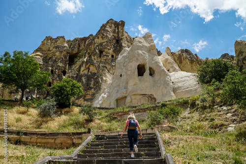 Cappadocia. A tourist, girl climbing the stairs to see ancient ruins of churches carved into the sandy rocks, selective focus photo
