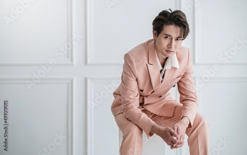 Portrait of Korean asian handsome smile friendly Business model man in pink suit sitting , business man smart with success, manager or executive with leadership office fashion workspace.