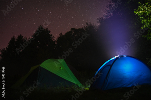 Camping tents amid bright night stars away from cities in the wild. Adventure traveling lifestyle. Concept wanderlust. Active weekend vacations wild nature outdoor.