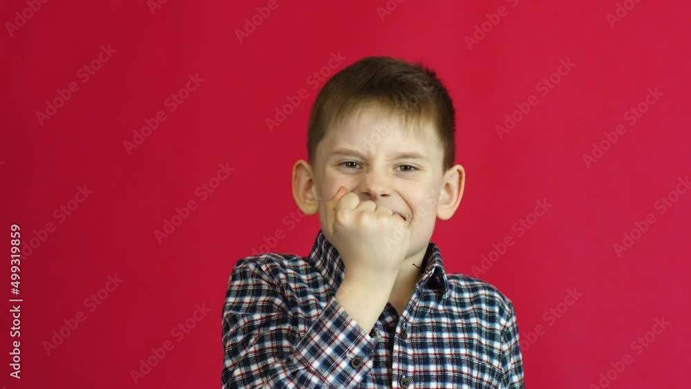 Caucasian peppy boy 8 years old victorious gesture yes with joy and success.Successful boy rejoices and says yes. Studio shooting on a red background. Concept of success and victory Caucasian peppy boy 8 years old victorious gesture yes with joy and success.Successful boy rejoices and says yes. Studio shooting on a red background. Concept of success and victory