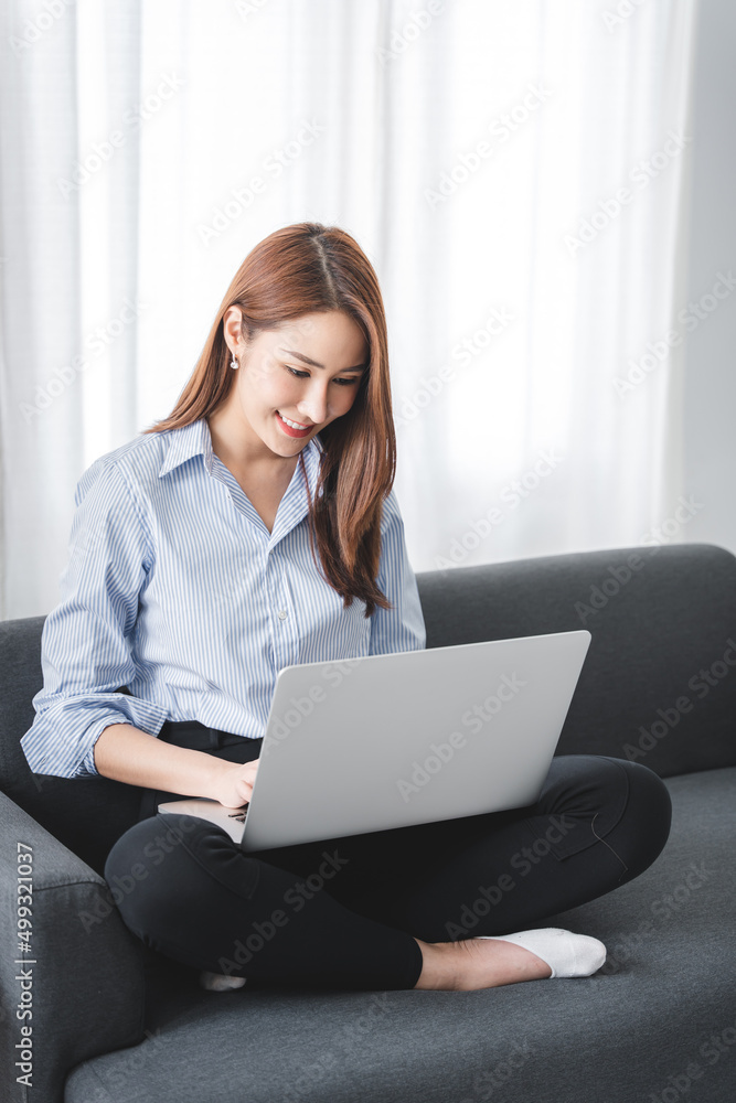 girl sitting on the sofa at home working on the computer. beautiful smile girl sitting on the sofa at home working on the computer. beautiful smile