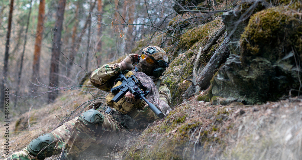 A special forces soldier during a clash in the forest. He calls his group's support on the walkie-talkie. Concept of modern military operations. A special forces soldier during a clash in the forest. He calls his group's support on the walkie-talkie. Concept of modern military operations.
