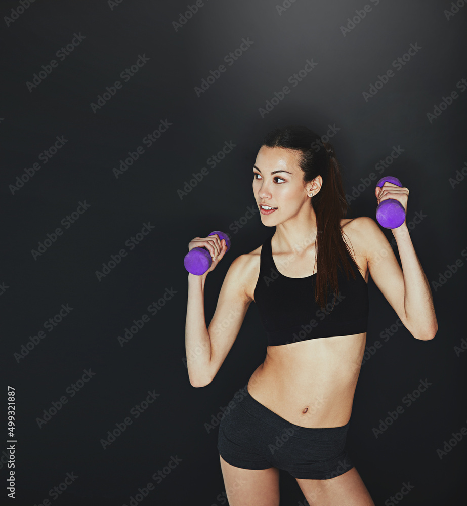 Stay dedicated. Shot of a young woman working out with dumbbells. Stay dedicated. Shot of a young woman working out with dumbbells.