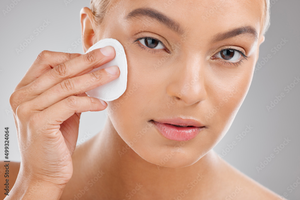 Beautiful skin requires commitment. Shot of an attractive young woman wiping her face with cotton against a studio background. Beautiful skin requires commitment. Shot of an attractive young woman wiping her face with cotton against a studio background.