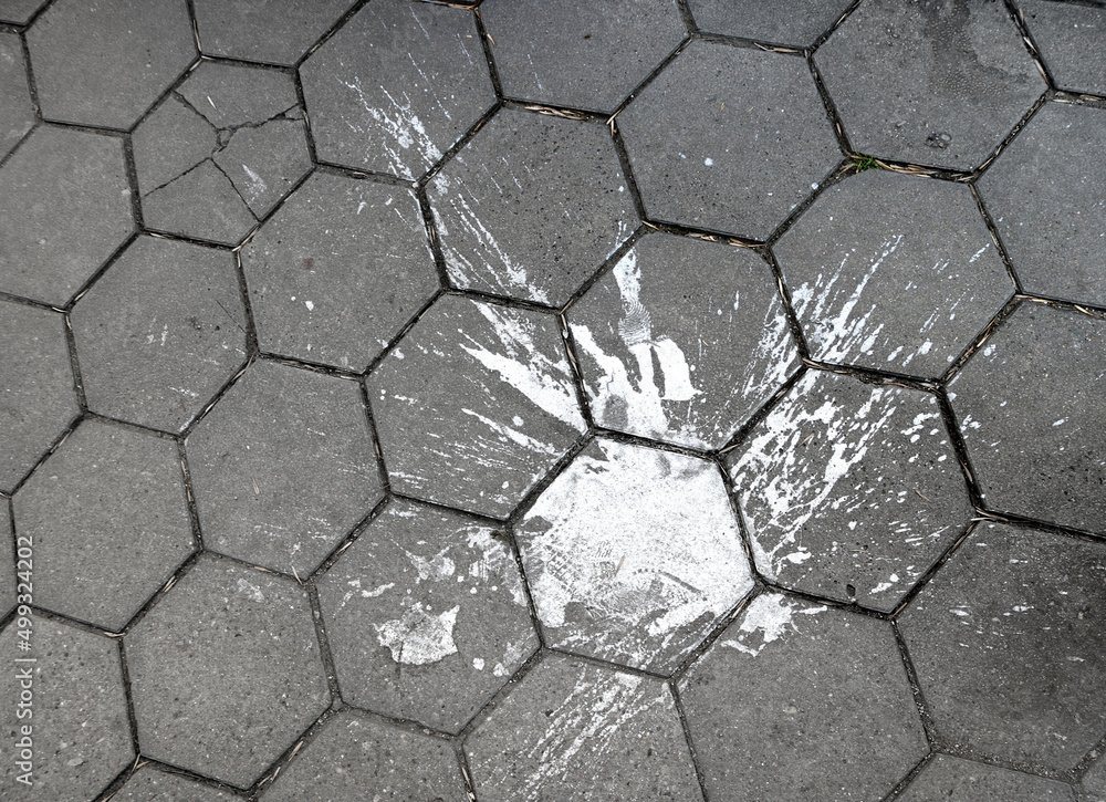 large splash of white paint fallen to the ground in the street, staining the gray hexagonal tiles large splash of white paint fallen to the ground in the street, staining the gray hexagonal tiles