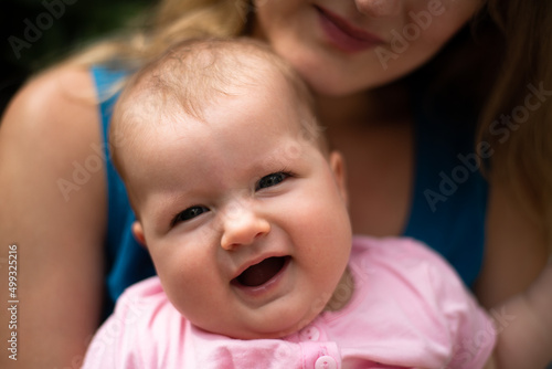 happy baby girl is smiling, mother holds child and looks on her