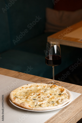 Four cheese pizza quattro formaggi with glass of wine on dark background. photo