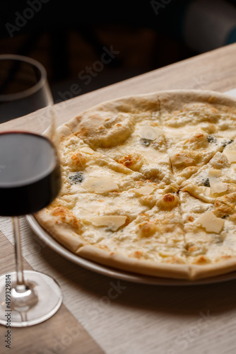 Four cheese pizza quattro formaggi with glass of wine on dark background. photo