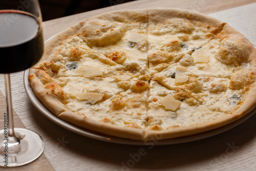 Four cheese pizza quattro formaggi with glass of wine on dark background.