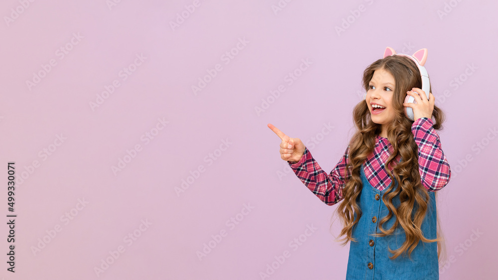 A child wearing headphones on an isolated purple background. a little girl listens to music. A child wearing headphones on an isolated purple background. a little girl listens to music.