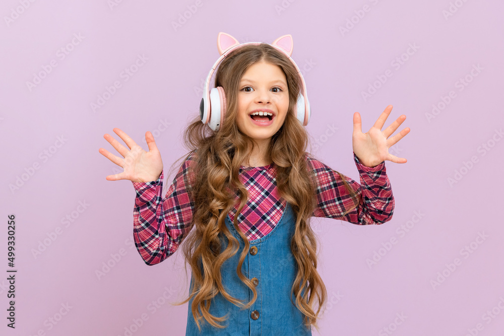 A girl in a denim skirt and a plaid jacket listens to music with headphones. The child is happy with the new headphones. A girl in a denim skirt and a plaid jacket listens to music with headphones. The child is happy with the new headphones.