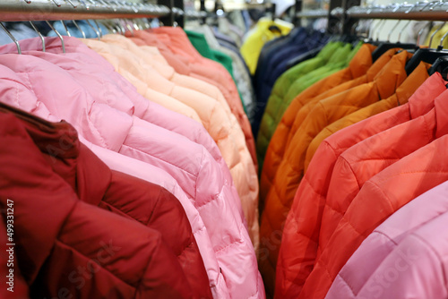 Colorful female jackets in a row on a hangers in the store. New spring fashion collection