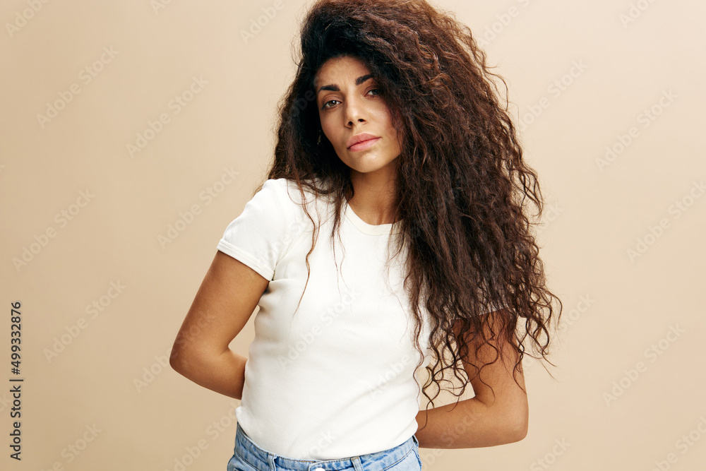 COOL OFFER. Upset serious beautiful curly Latin female in white t-shirt crossing hand. Fashion woman portrait. Studio shoot over beige background. Copy space, free place for design ad COOL OFFER. Upset serious beautiful curly Latin female in white t-shirt crossing hand. Fashion woman portrait. Studio shoot over beige background. Copy space, free place for design ad