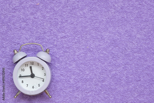 Alarm clock on a lilac suede background. There is space for text. Concept photo