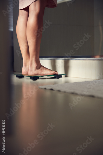 Stop weighing yourself down. Shot of an unrecognizble woman weighing herself on a scale at home.