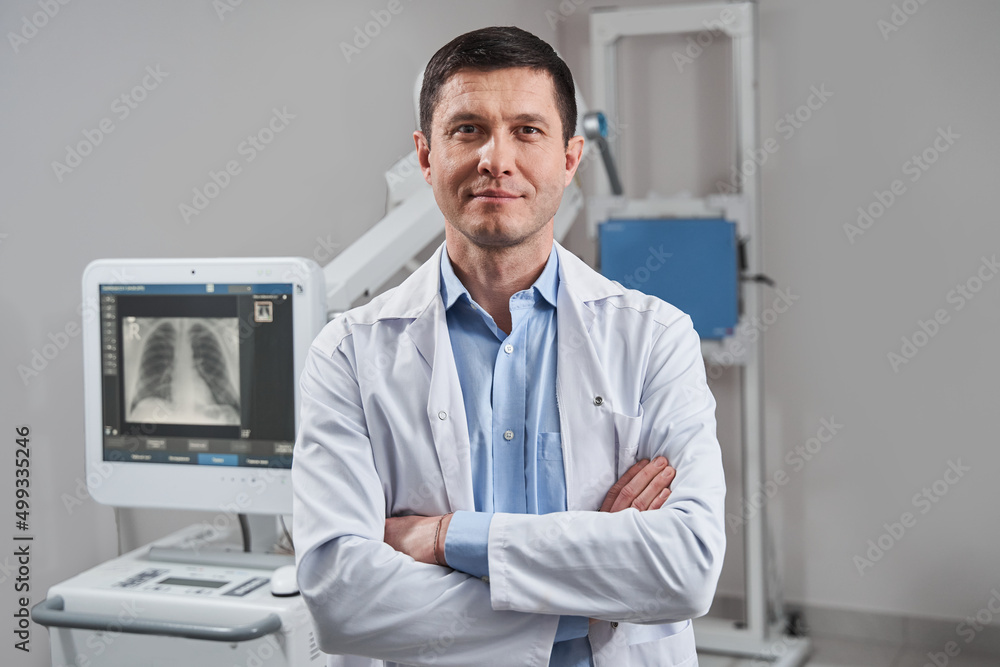 Doctor with a stethoscope around his neck smiling widely in a welcoming manner while posing