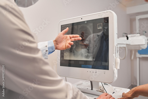 Doctor pointing at the monitor screen with view of the lungs after fluorography and discussing it