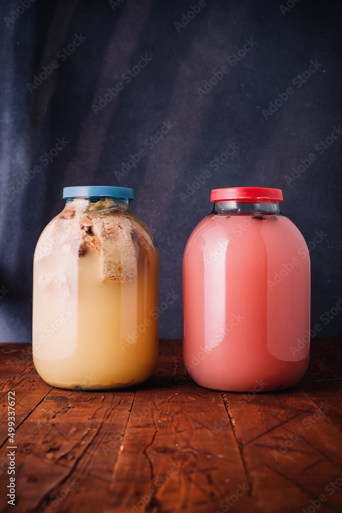 Two jars of homemade kvass, wheat or rye bread and hibiscus kvas, on wooden dark rustic background. National slavic summer tasty beverage Two jars of homemade kvass, wheat or rye bread and hibiscus kvas, on wooden dark rustic background. National slavic summer tasty beverage