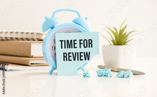 blue alarm clock lies on a blue background next to a card with the text time for feedback. Conceptual business photo on the topic of product evaluation.