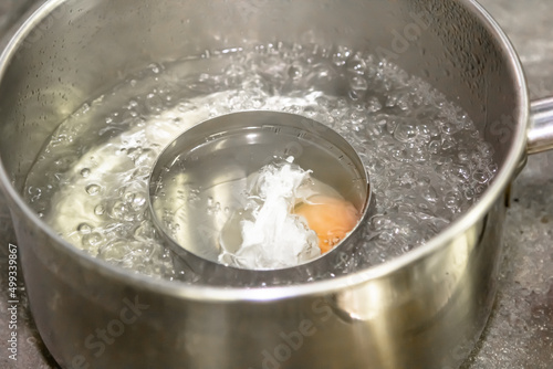 Poaching fresh eggs in a pan of water in an authentic kitchen environment. photo