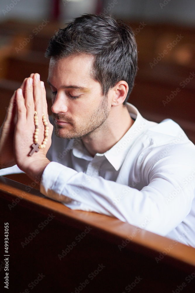 He knows where his strength comes from. Shot of a young man praying in a church. He knows where his strength comes from. Shot of a young man praying in a church.