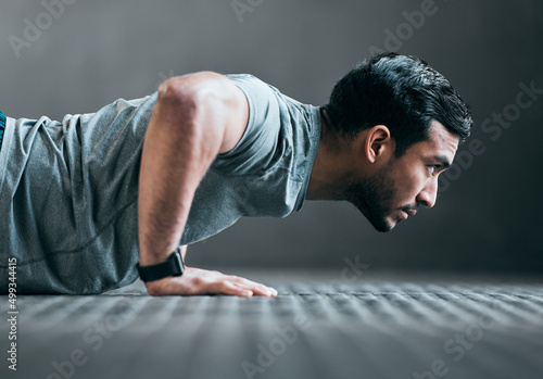 Forward focus. Cropped shot of a handsome young male athlete doing pushups against a grey background. photo
