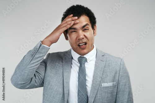 I stayed out late last night celebrating that new partnership. Studio shot of a businessman looking stressed while standing against a grey background.