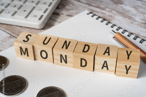 「SUNDAY MONDAY」と書かれた積み木、電卓、ノート、ペン、コイン