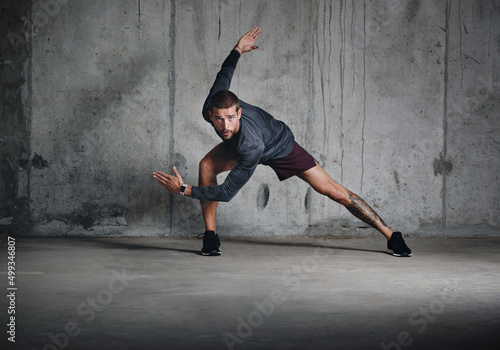 Getting ready to dash. Full length shot of a sporty young man stretching while exercising inside a parking lot.