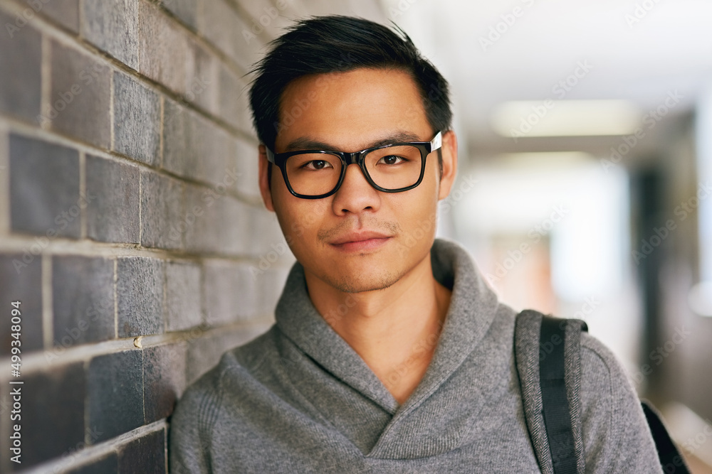 Fototapeta premium Im here to get my learn on. Cropped portrait of a handsome young male university student standing in a campus corridor.