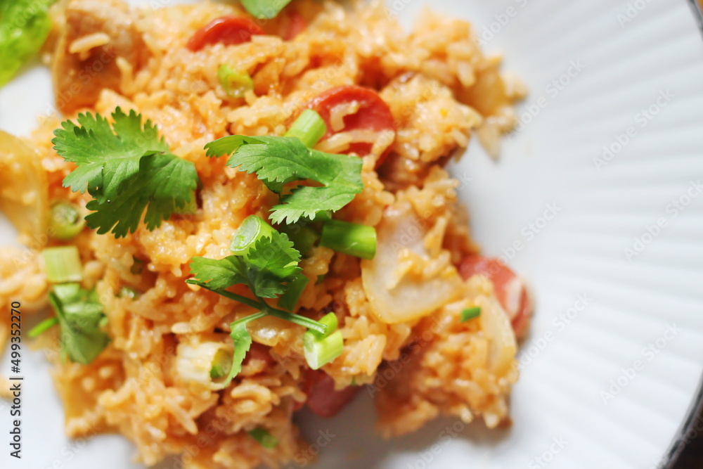 Close-up, pork and sausage fried rice served in a plate with lettuce and coriander garnish. Fried rice is a street food that is sold in Thailand. Close-up, pork and sausage fried rice served in a plate with lettuce and coriander garnish. Fried rice is a street food that is sold in Thailand.