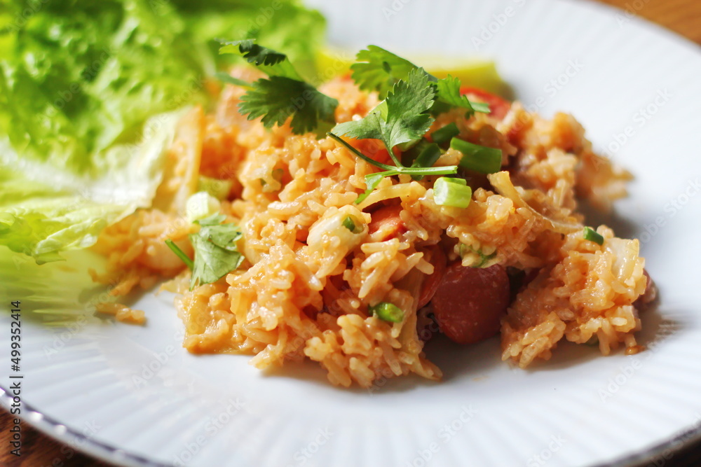 Close-up, pork and sausage fried rice served in a plate with lettuce and coriander garnish. Fried rice is a street food that is sold in Thailand. Close-up, pork and sausage fried rice served in a plate with lettuce and coriander garnish. Fried rice is a street food that is sold in Thailand.