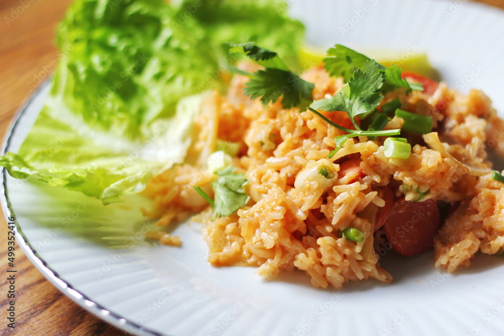 Close-up, pork and sausage fried rice served in a plate with lettuce and coriander garnish. Fried rice is a street food that is sold in Thailand. Close-up, pork and sausage fried rice served in a plate with lettuce and coriander garnish. Fried rice is a street food that is sold in Thailand.