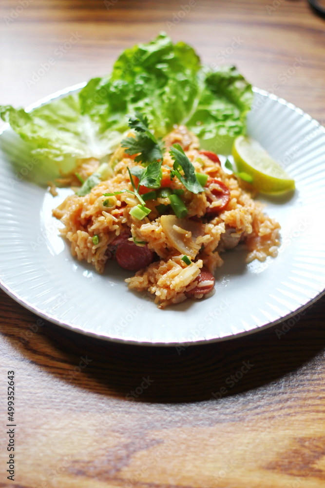 Vertical picture, pork and sausage fried rice served in a plate with lettuce and coriander garnish. Fried rice is a street food that is sold in Thailand.