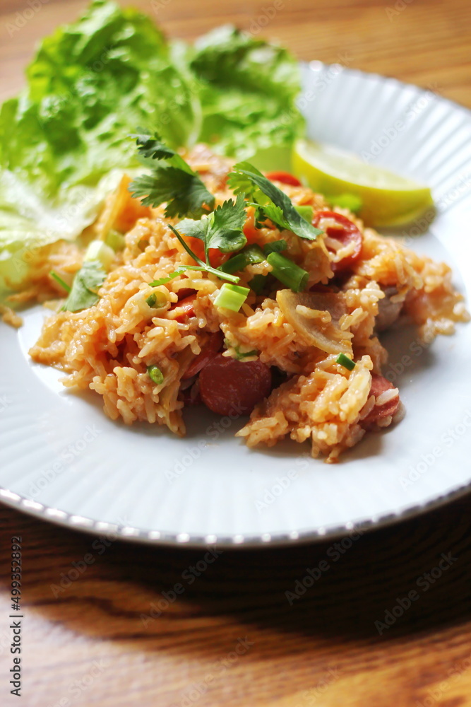 Vertical picture, pork and sausage fried rice served in a plate with lettuce and coriander garnish. Fried rice is a street food that is sold in Thailand. Vertical picture, pork and sausage fried rice served in a plate with lettuce and coriander garnish. Fried rice is a street food that is sold in Thailand.