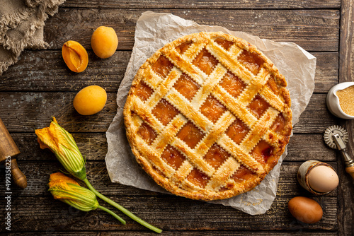 Summer apricot or peach pie homemade on wooden background, top view. Delicious fruit dessert. Fruit cake. Copy space.