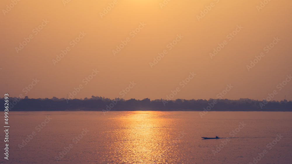 Beatiful golden sunlight landscape and silhouette with small fishing boat on the river