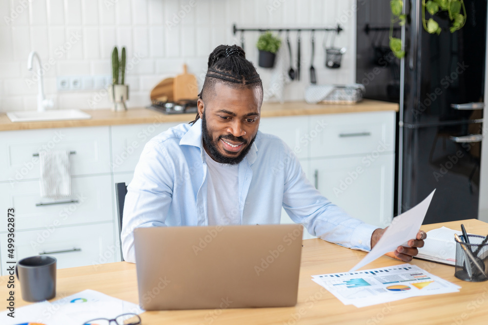 Portrait of confident African American businessman freelancer analyzing annual sales chart. Man working remotely from home