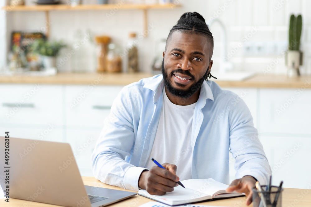 Distance learning, online education. Portrait of smiling African American adult male freelancer working remotely from home, looking at camera, smiling Distance learning, online education. Portrait of smiling African American adult male freelancer working remotely from home, looking at camera, smiling