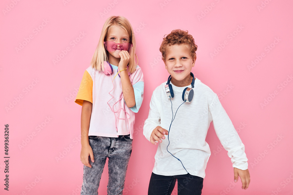 funny little boy and girl entertainment headphones playing pink color background