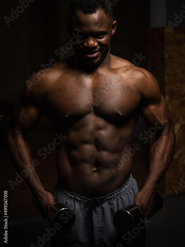 Muscular dark-skinned man doing an exercise with dumbbells. 