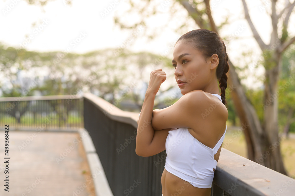 Naklejka premium A young fitness woman in sportswear exercising in city park, Healthy and Lifestyles.