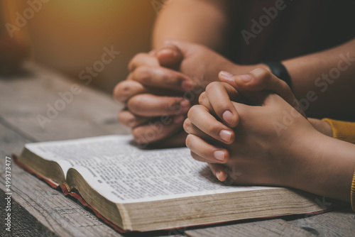 Close-up two christian read bible. Hands folded in prayer on a Holy Bible on wooden table. online group worship, World Day of Prayer, international day of prayer, hope, gratitude, thankful, trust © Stratocaster