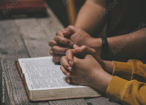 Close-up two christian read bible. Hands folded in prayer on a Holy Bible on wooden table. online group worship, World Day of Prayer, international day of prayer, hope, gratitude, thankful, trust © Stratocaster